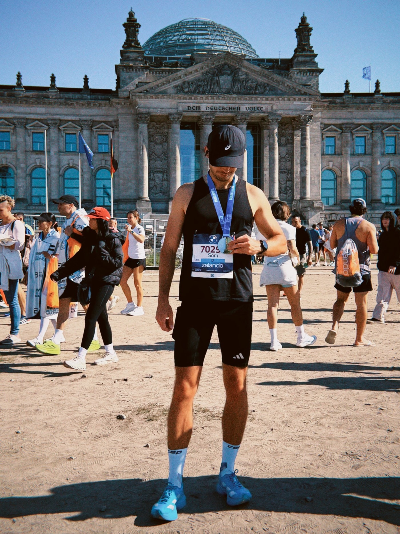 Sam holding his Berlin Marathon medal outside the Reichstag