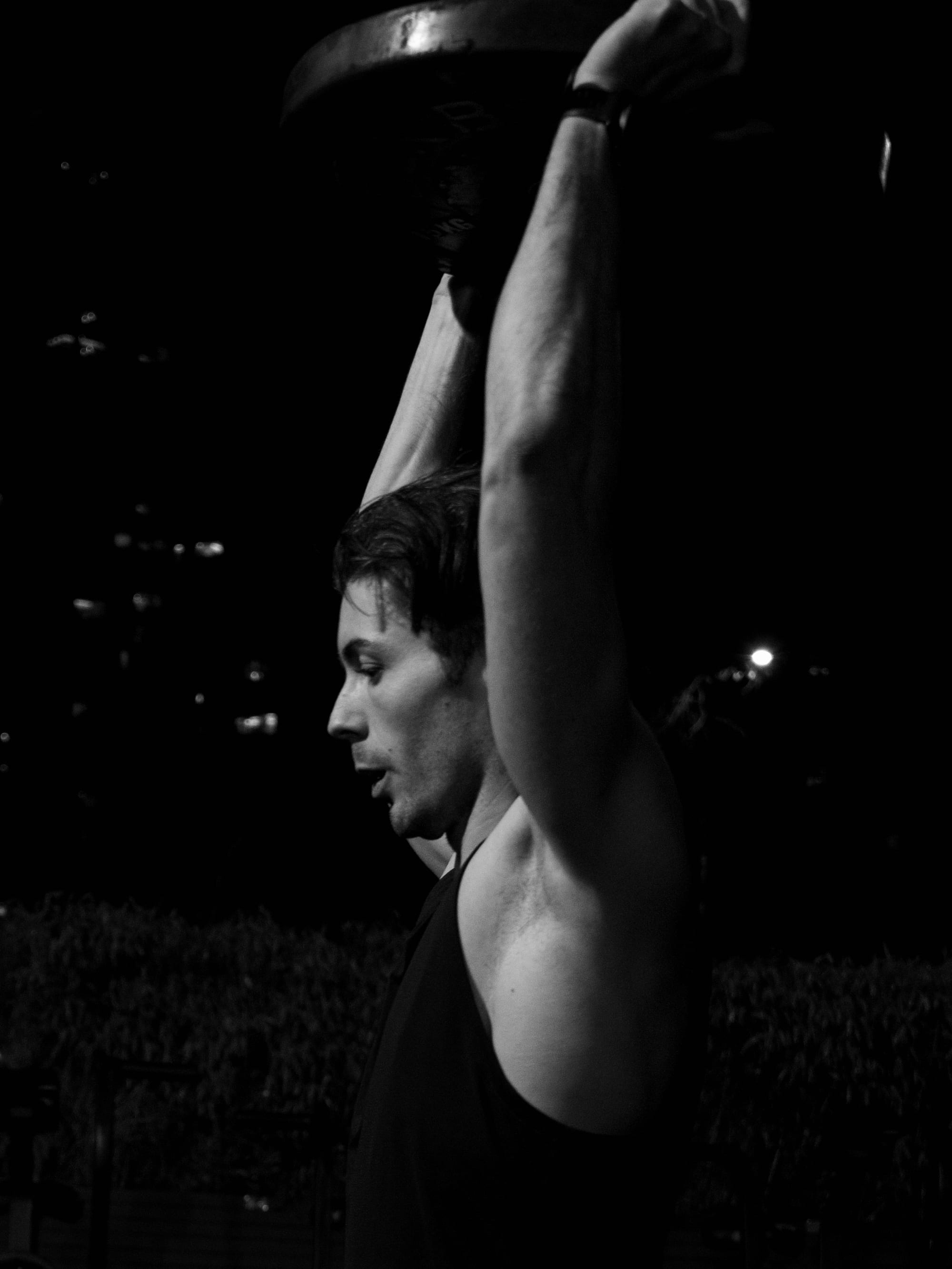 Sam lifting a kettlebell overhead at night