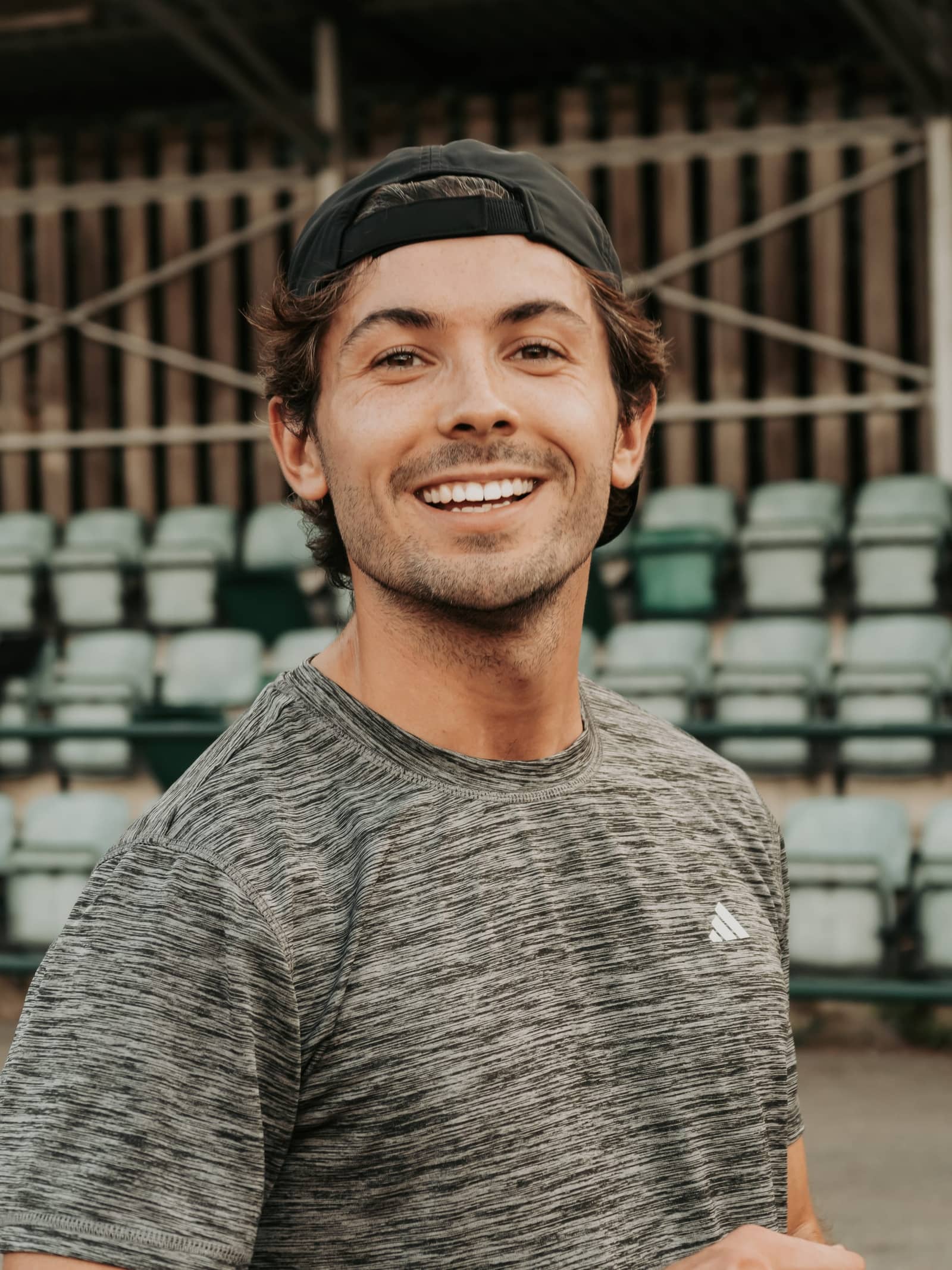 Portrait of Sam smiling beside a running track
