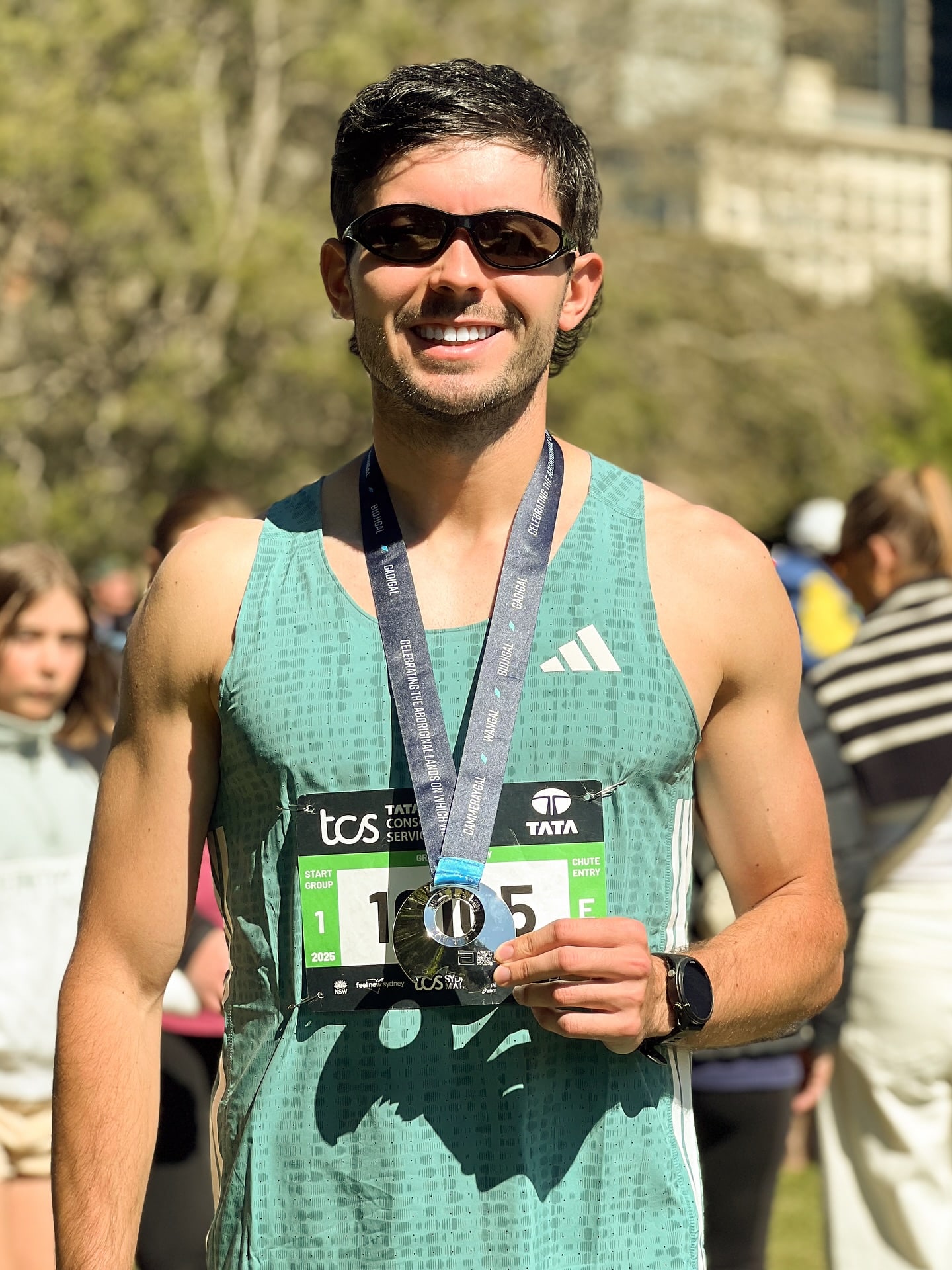 Sam holding his Sydney Marathon medal